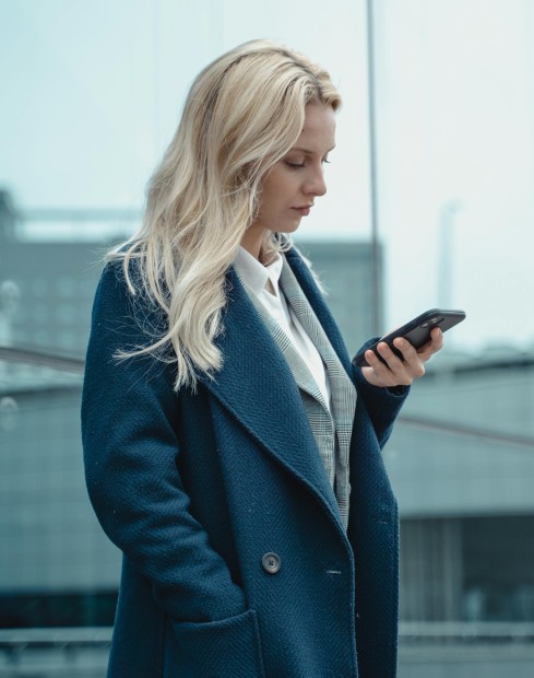 A businesswoman in professional attire engaged with her smartphone
